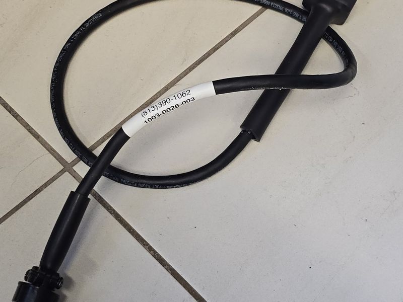 Black machine-control cable with a printed part-number label