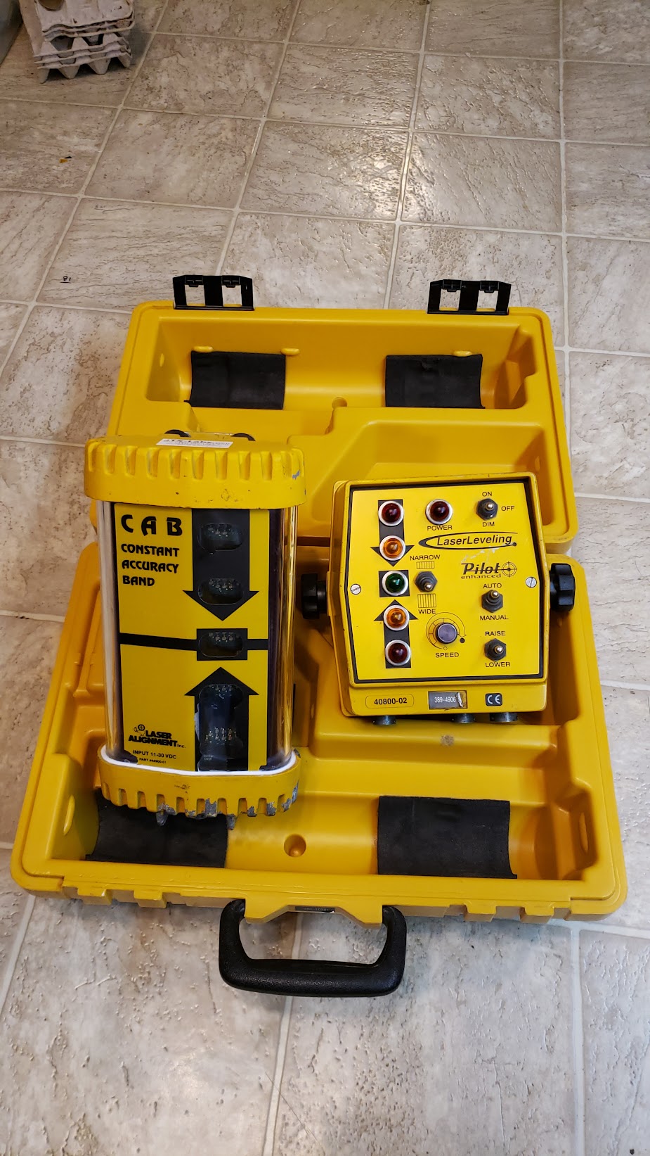 Laser leveling kit displayed in a yellow carrying case, featuring a laser tool and control panel for accurate leveling in construction projects.